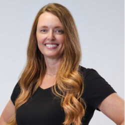 Jessica - Staff member at Community Real Estate. A smiling white women, with ginger hair with blond highlights, wearing a black tshirt.